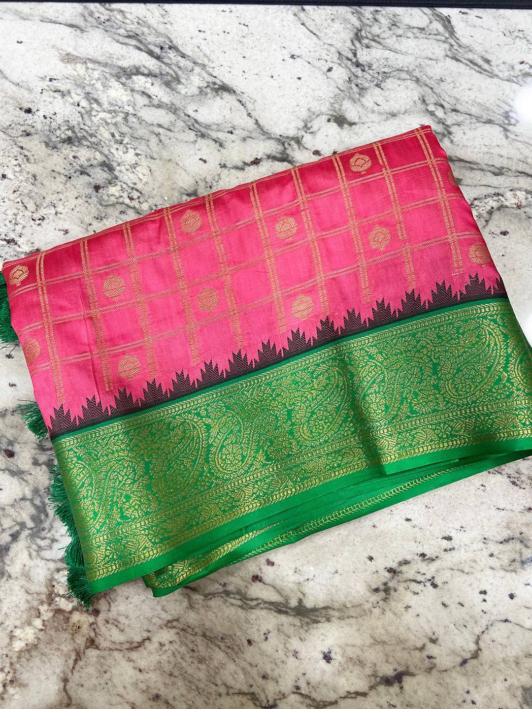 Blush pink Banarasi saree with green border on marble surface