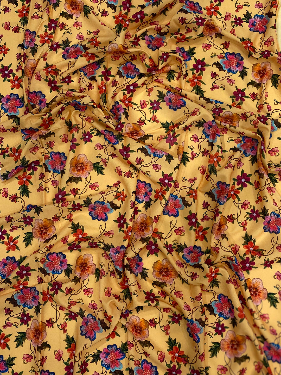 Close-up of yellow fabric with intricate floral embroidery.