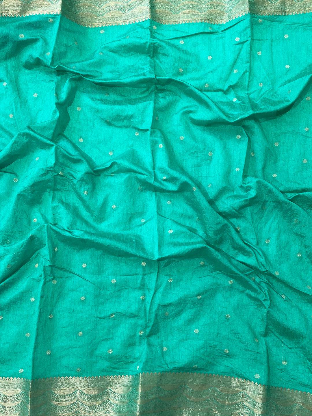 Close-up of turquoise organza saree fabric with gold zari