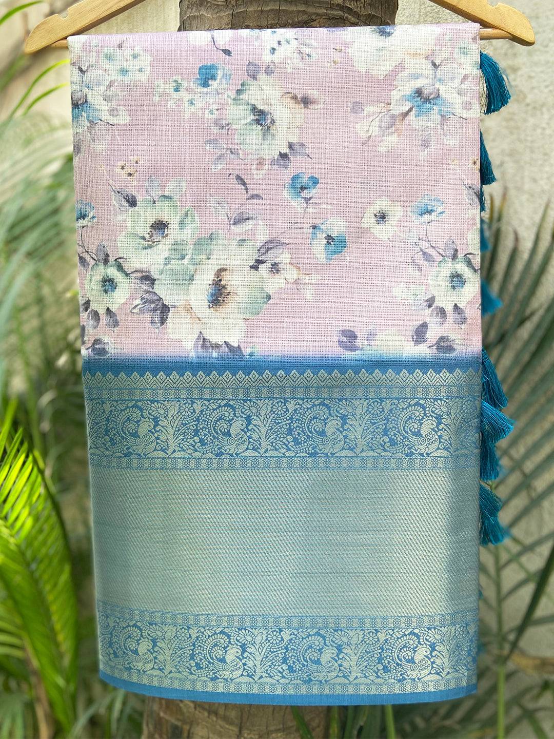 Floral print saree with blue zari border hanging on a tree