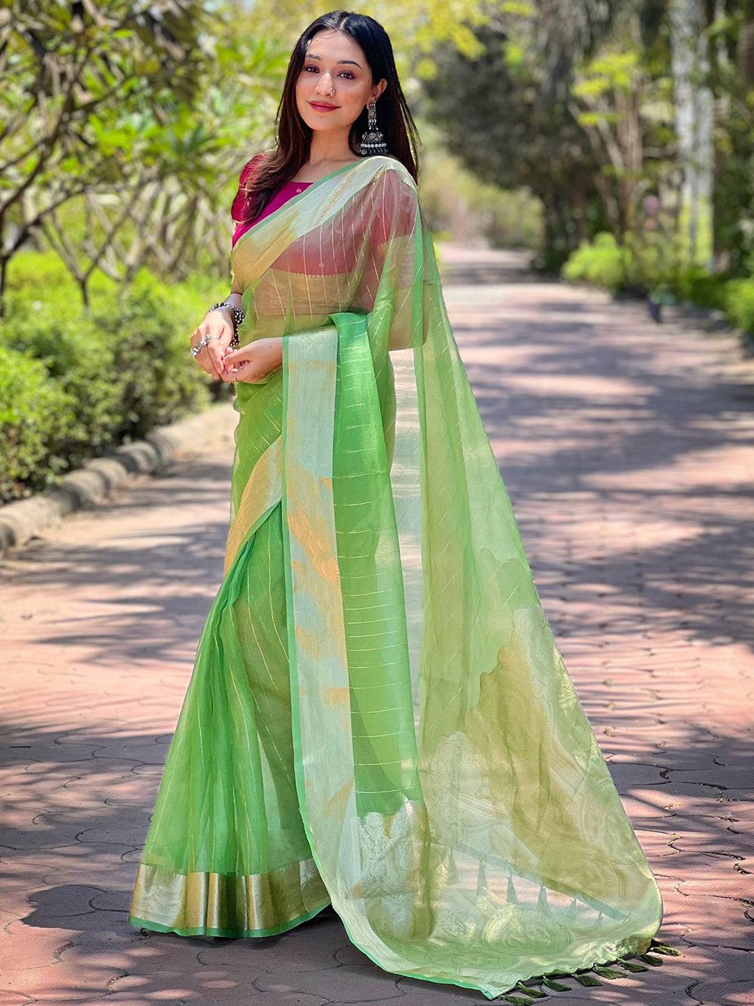 Model in green organza saree, showcasing gold zari weaving.