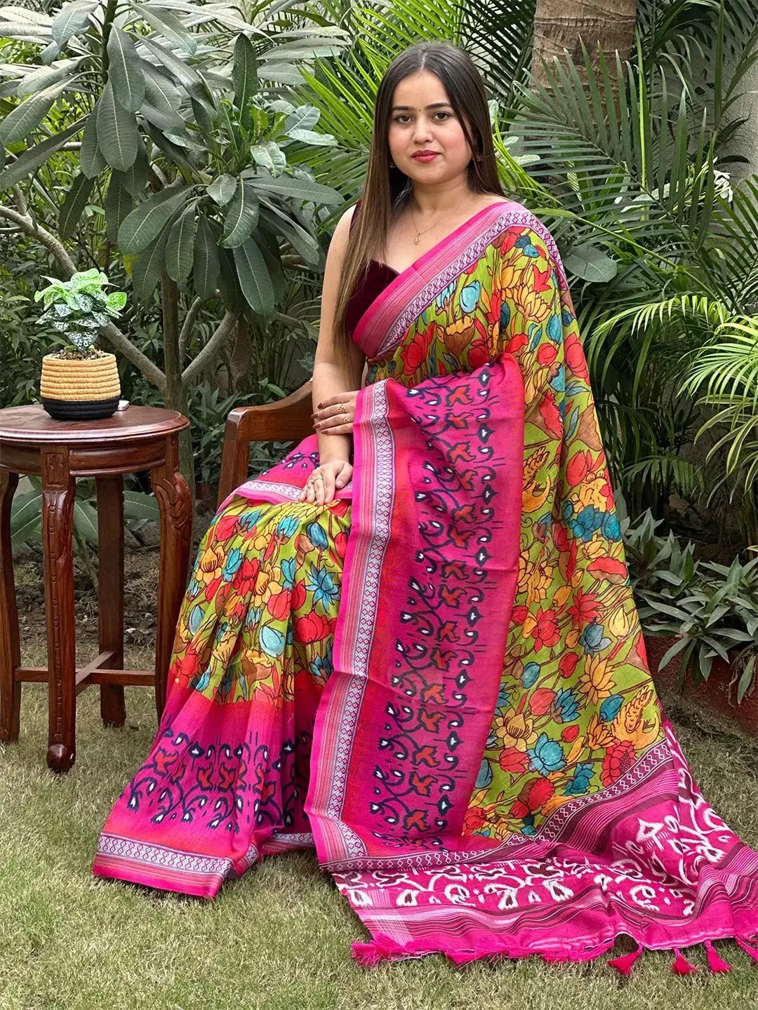 Vibrant floral Ikkat printed saree with pink border, seated pose