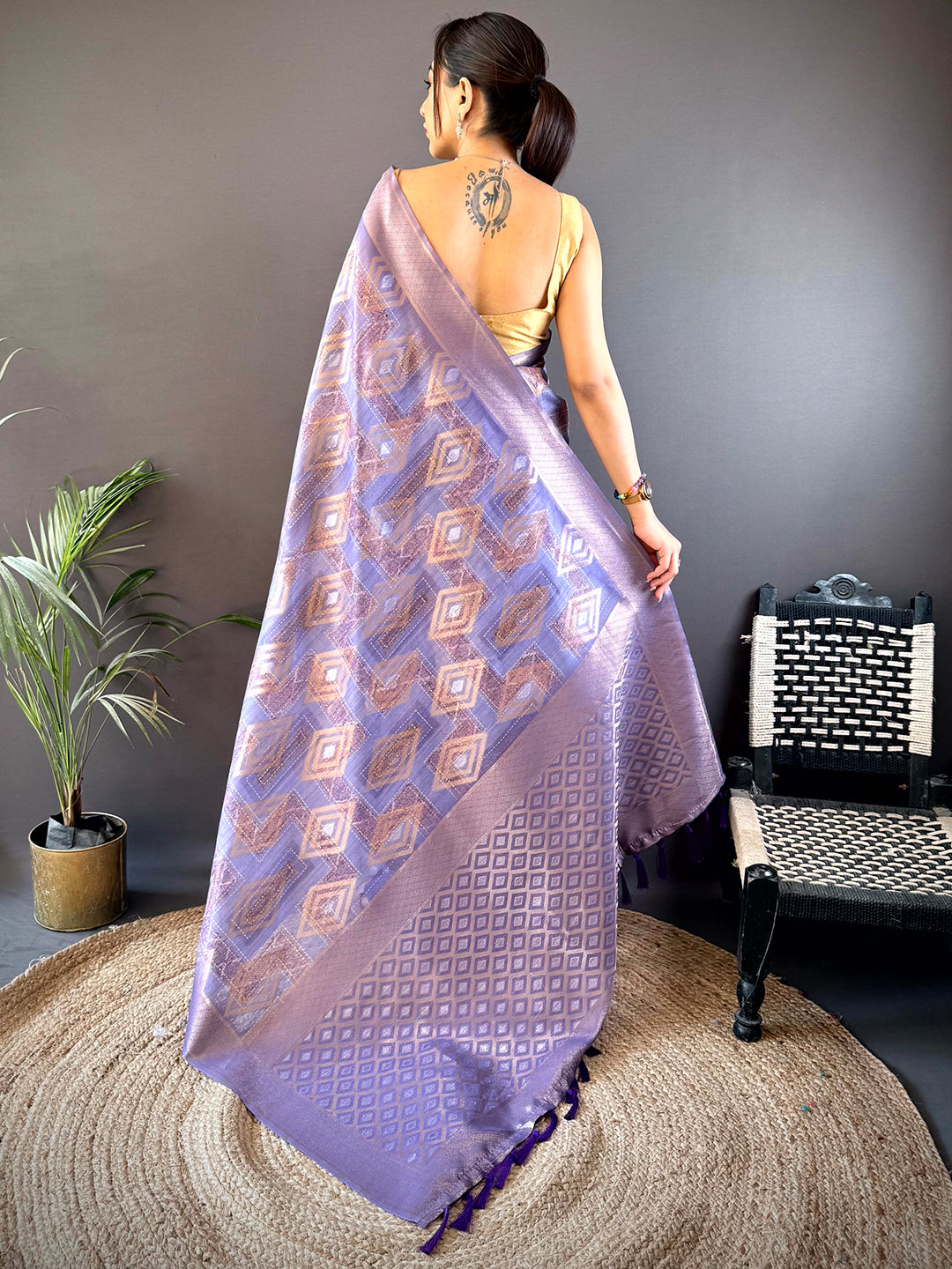 Back view of Lavender Banarasi Silk Katan Geometric Saree showcasing intricate gold motifs and a detailed pallu with tassel accents.