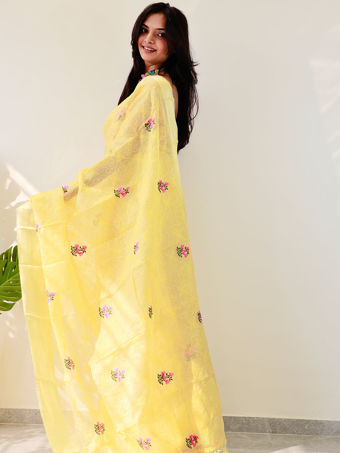 Model showcasing yellow chiffon satin saree with flower embroidery.