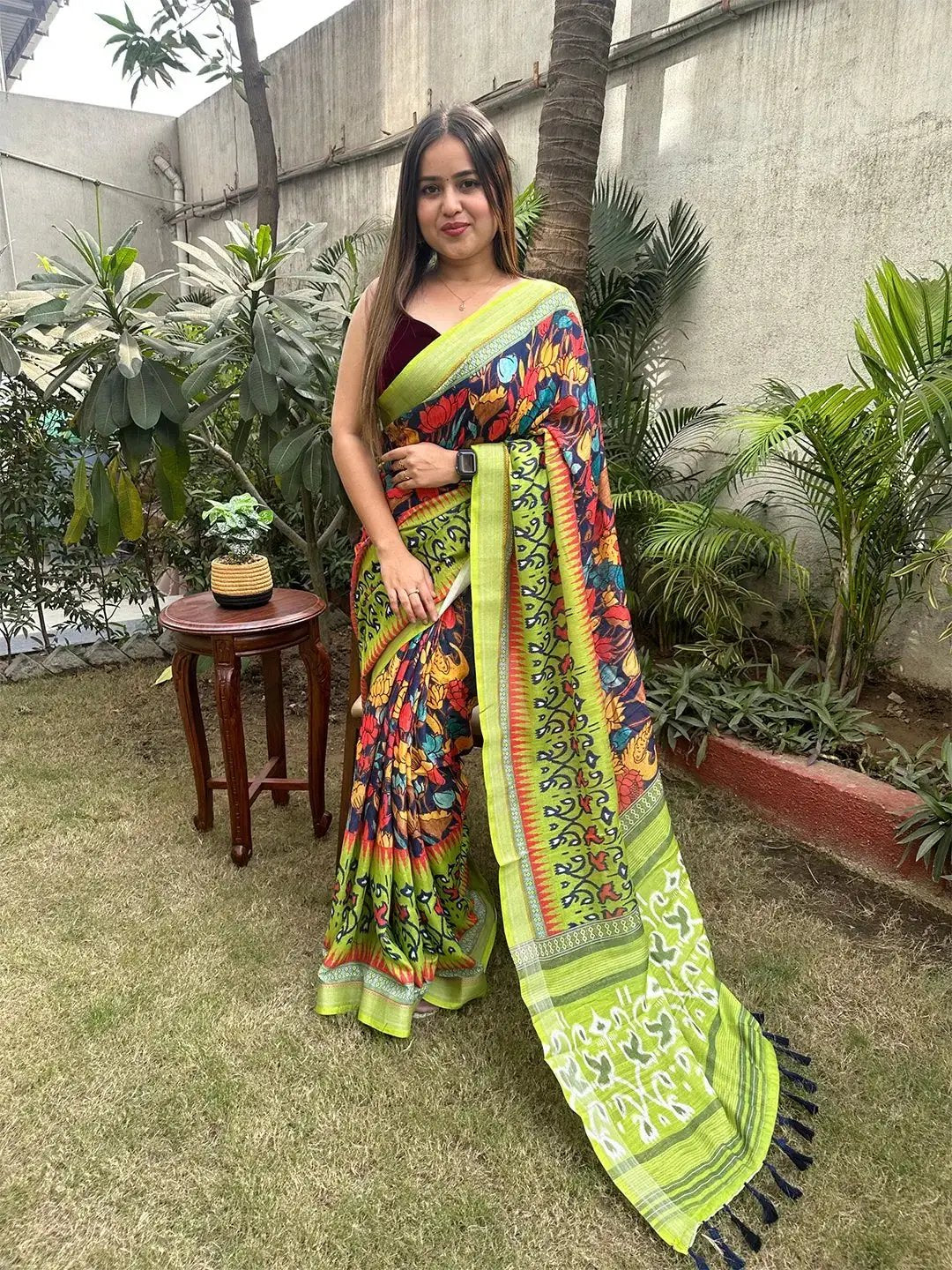 Model wearing floral Ikkat saree with green border in garden