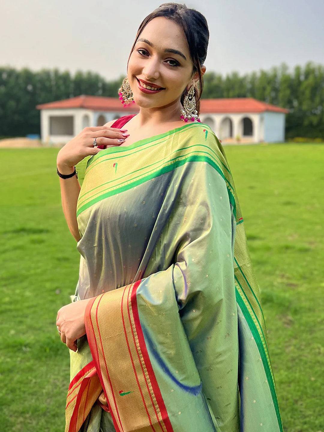 Woman wearing light green Paithani saree with Ganga Jamuna border.