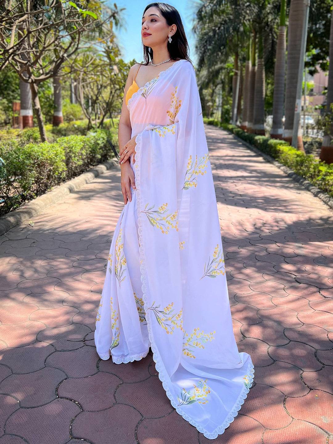 Model posing in white floral satin georgette saree with zircon border