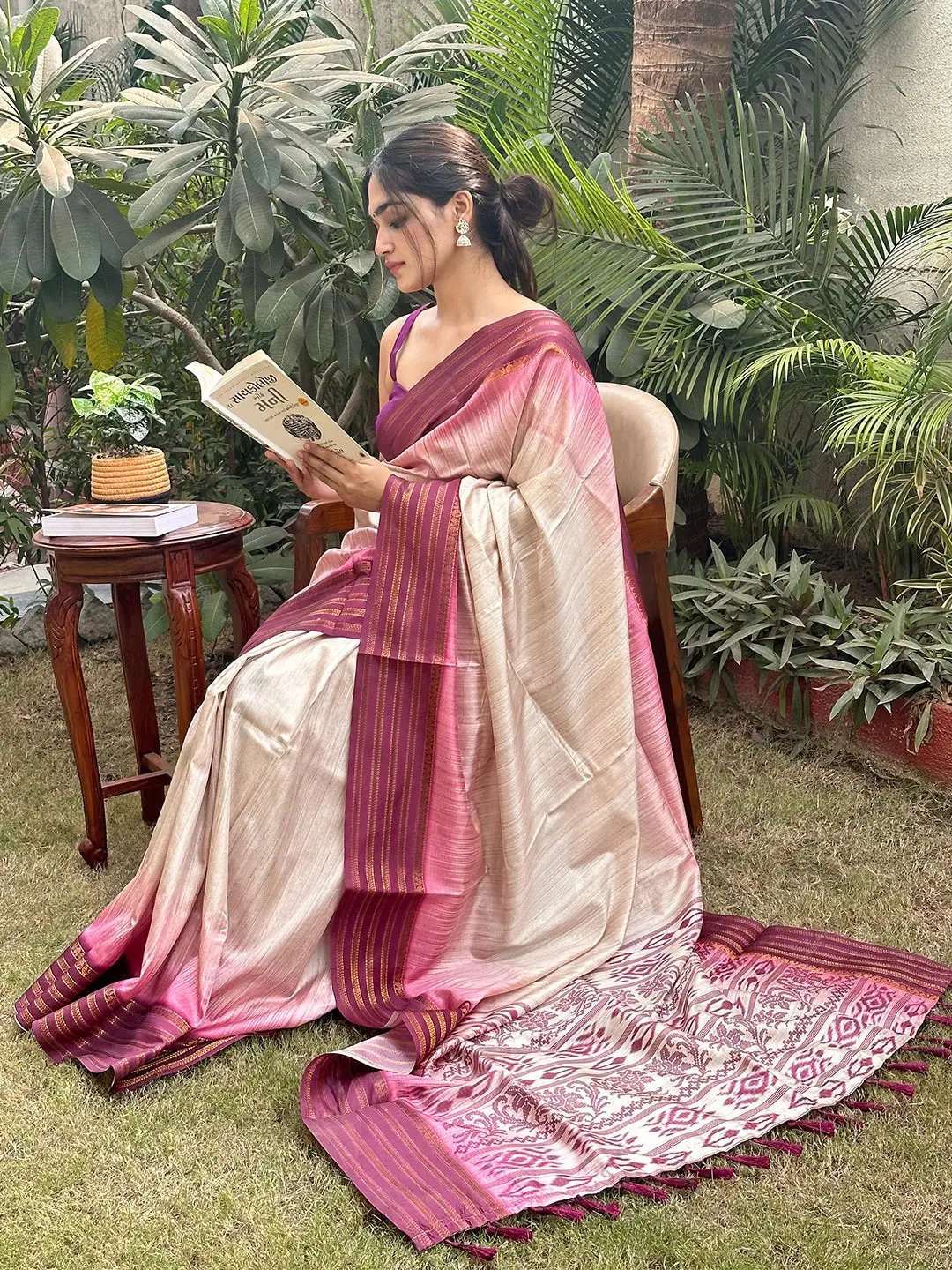 Woman reading in wine Ikkat Ghicha saree outdoors