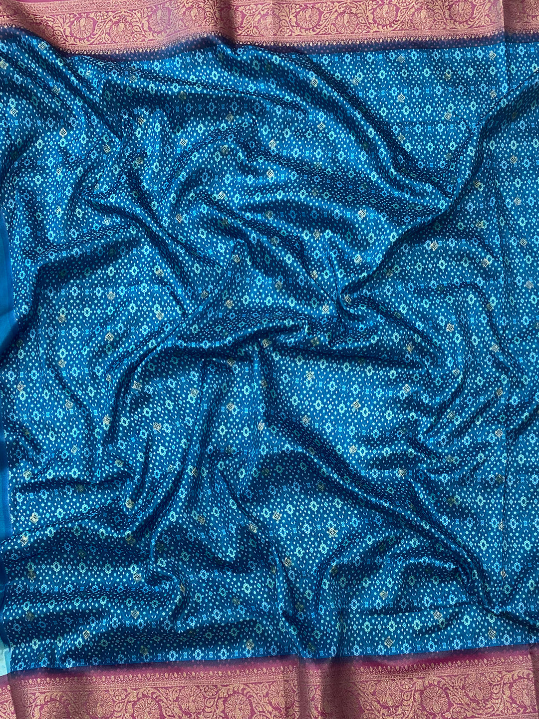 Close-up of soft silk blue Banarasi saree fabric with detailed patterns.