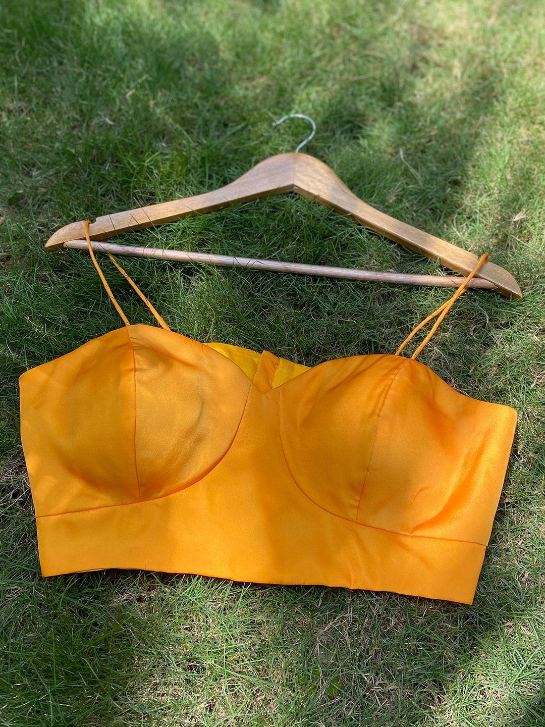 Yellow satin blouse on hanger on grass