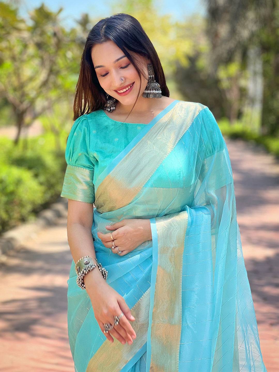 Turquoise organza saree with gold zari border, worn by model