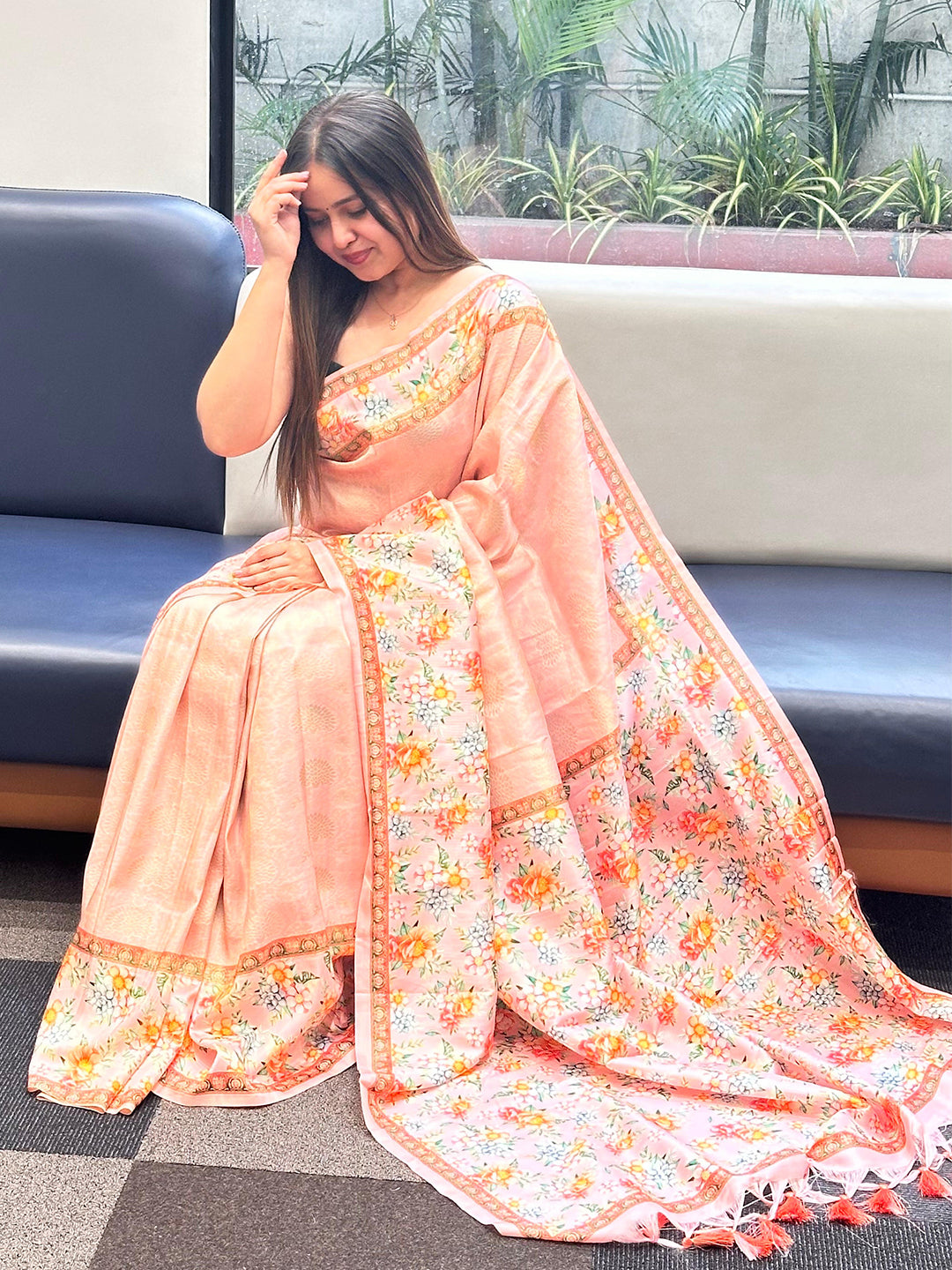 Seated woman in a beautiful Kanjivaram saree with floral patterns.