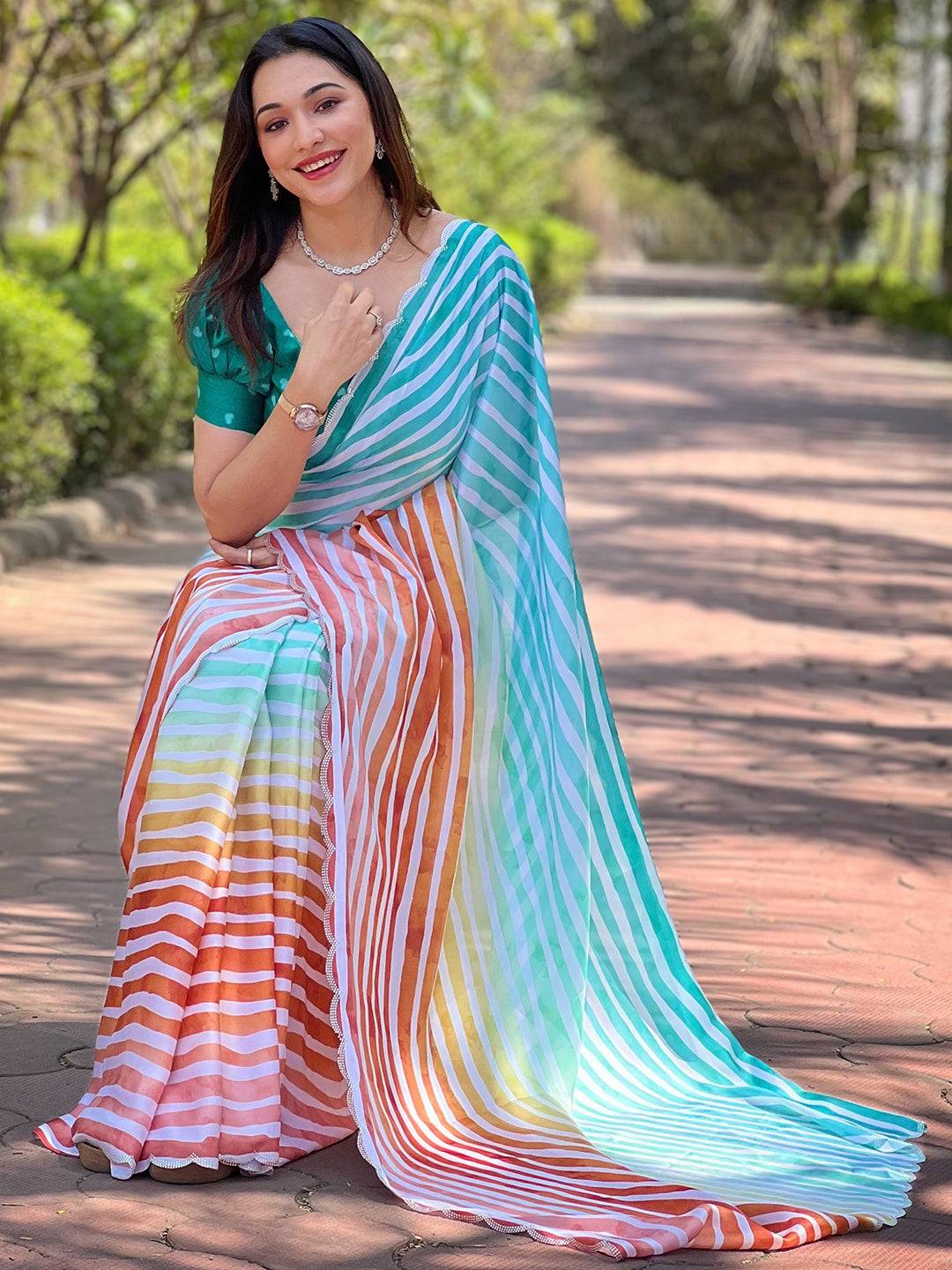 Woman in striped Leheriya saree sitting outdoors