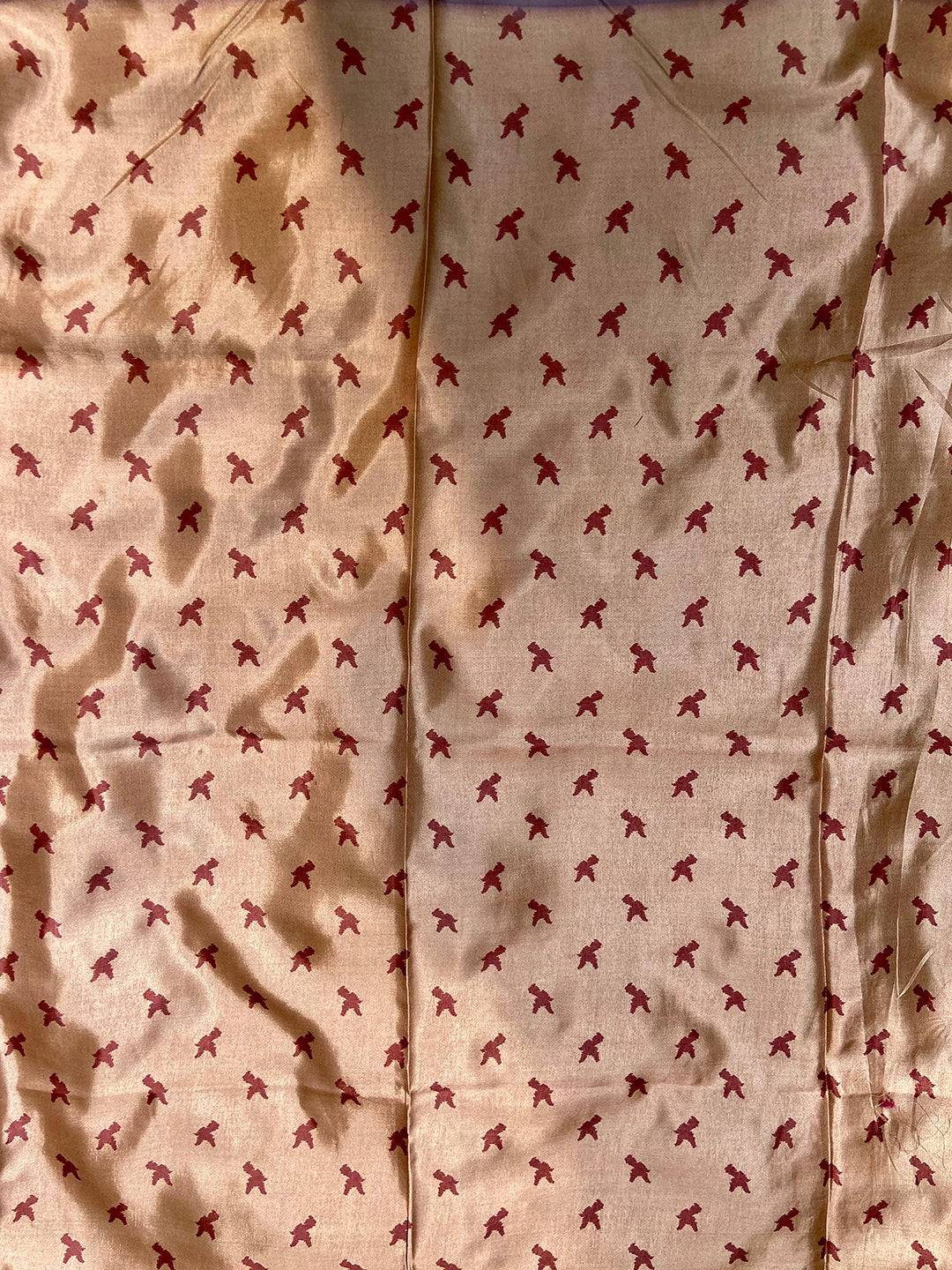 Close-up of saree with small red bird pattern on brown fabric.