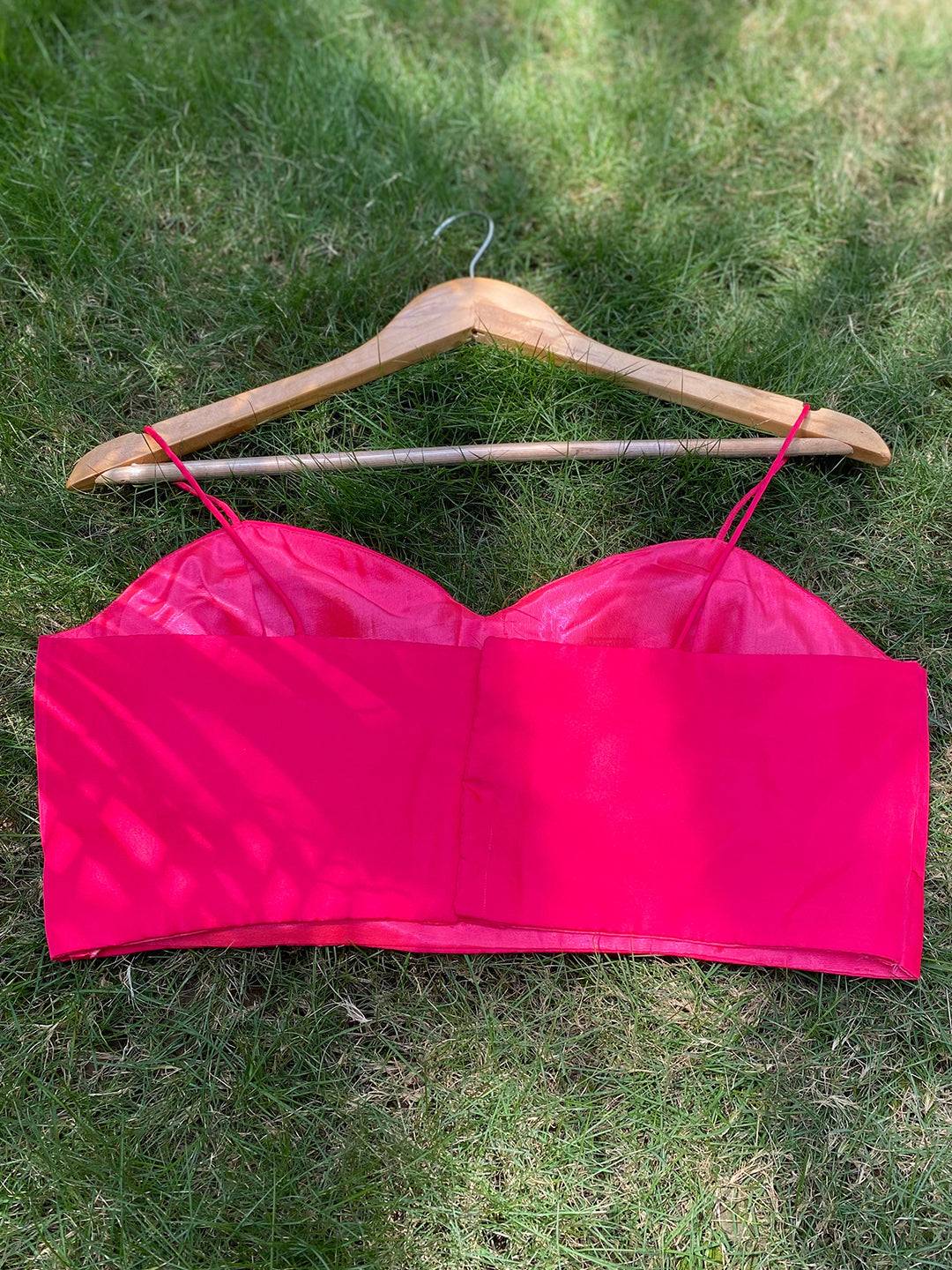 Back of bright pink sleeveless blouse on hanger