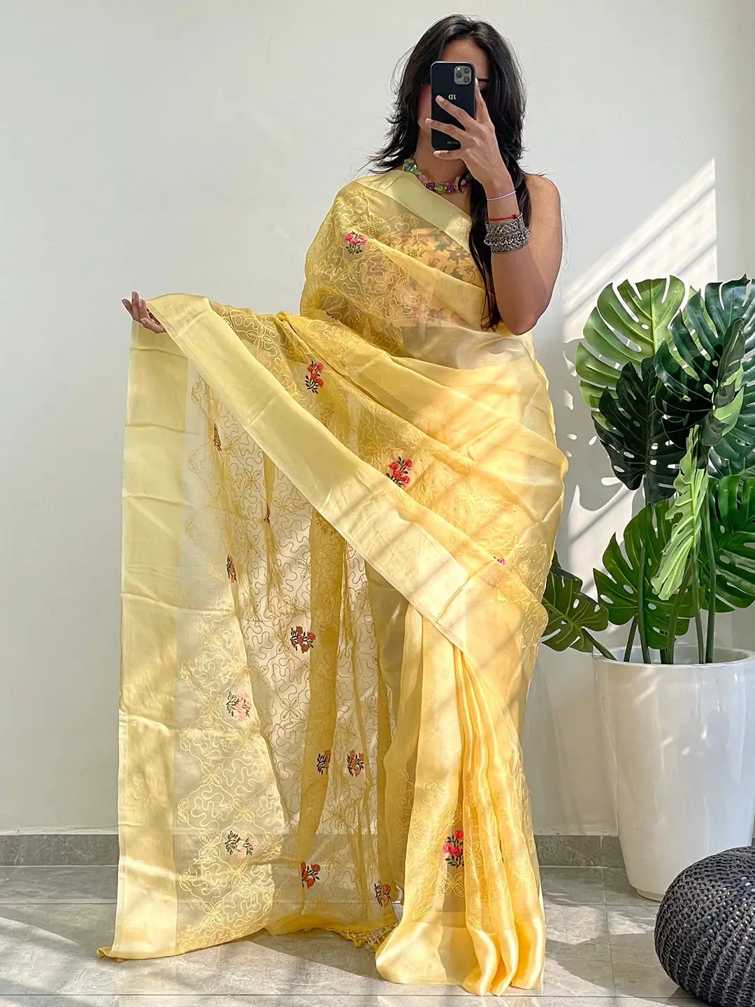 Model taking selfie in yellow chiffon satin saree with floral design.