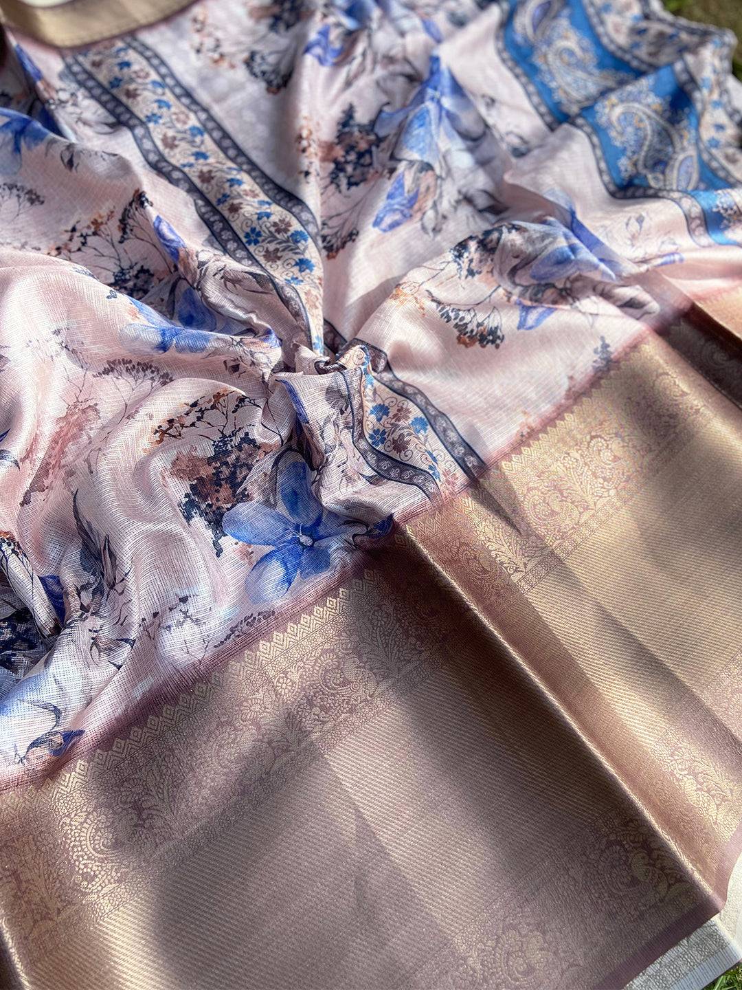 Close-up of light pink saree with intricate floral print and gold border