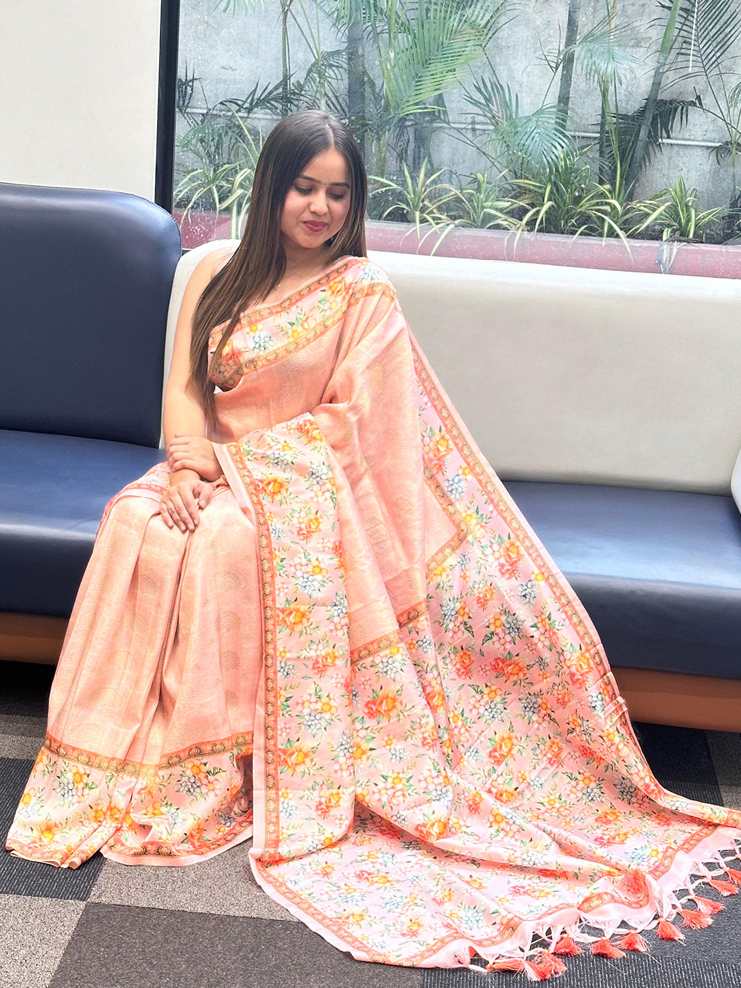 Woman sitting in a Kanjivaram saree featuring floral prints.