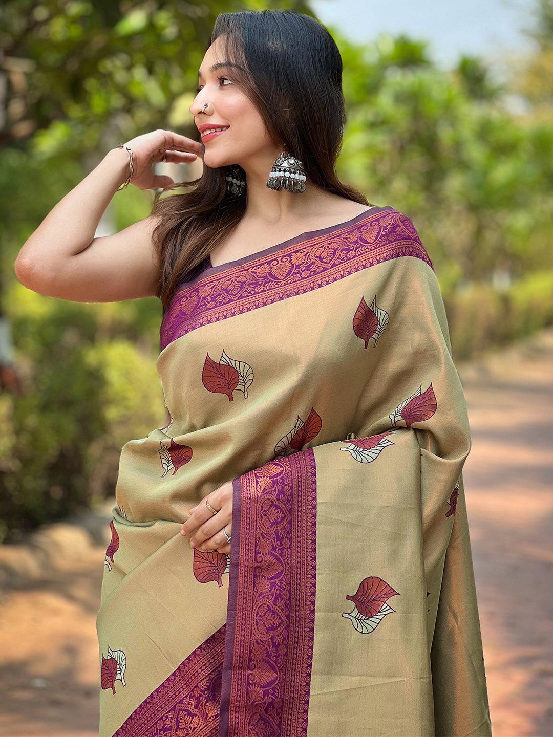 Woman in light green saree with maroon border and leaf motifs