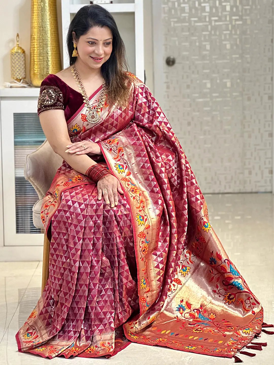 Seated model in wine silk blend Paithani saree with vibrant zari.