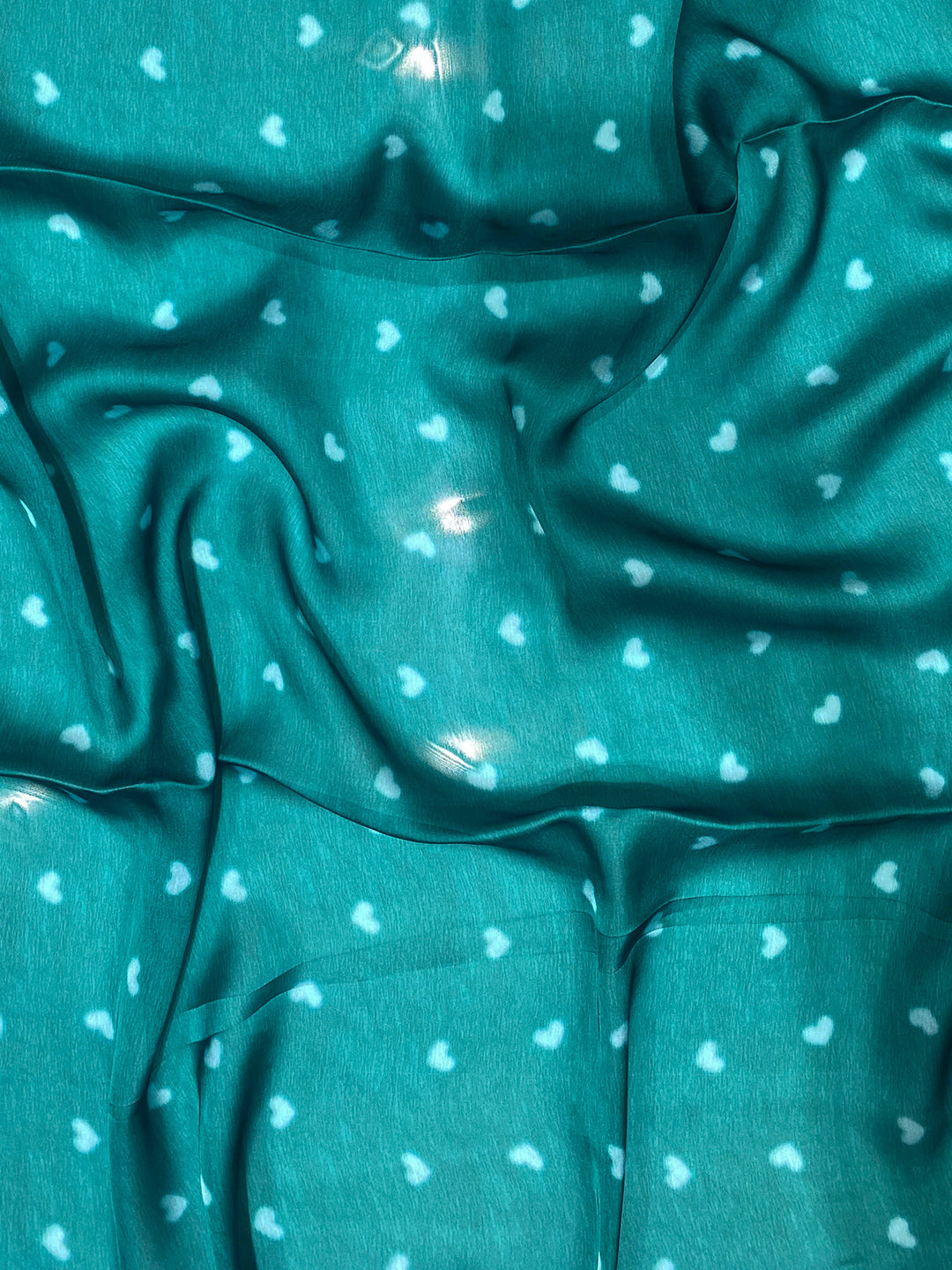 Close-up of teal fabric with heart patterns