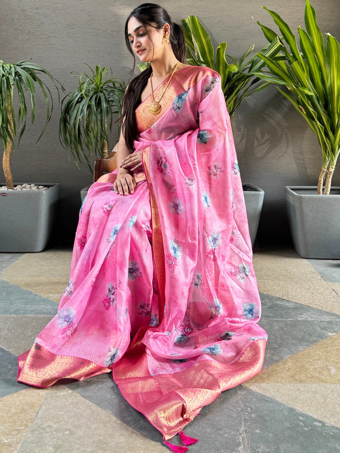 Woman seated wearing pink floral print Kota silk saree