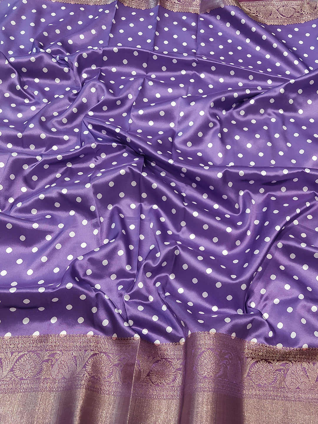 Close-up of purple saree with polka dots and zari border.