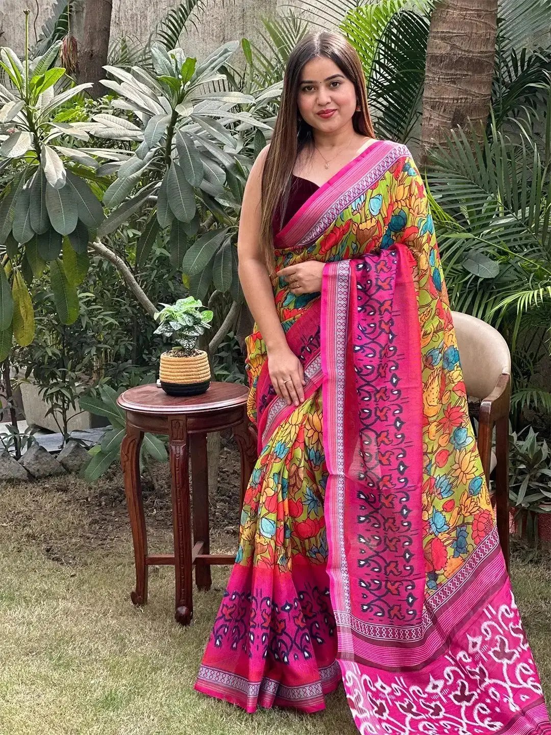 Colorful floral Ikkat saree with intricate pink border, standing pose