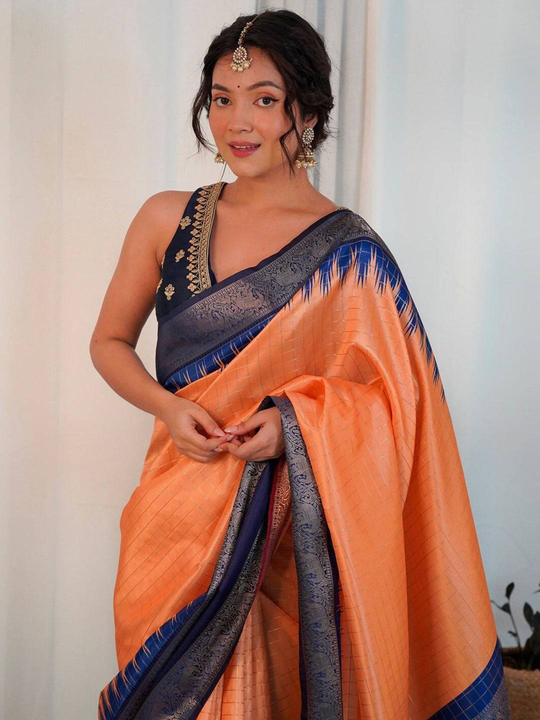 Close-up of orange Banarasi silk saree with blue zari work.