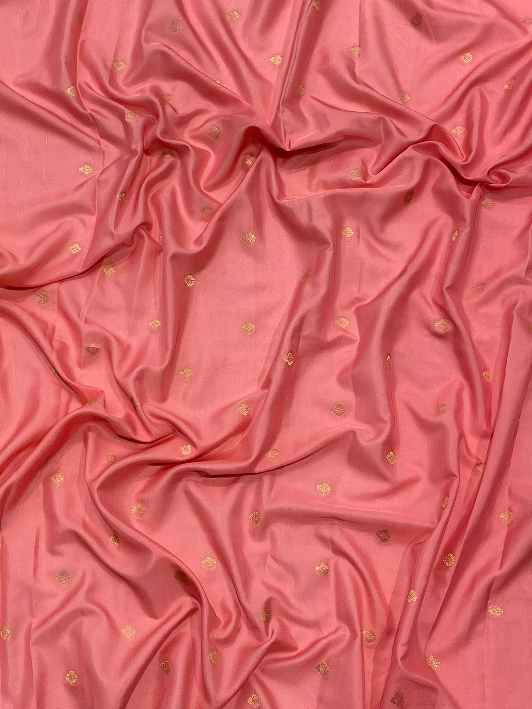 Close-up of pink ombre silk fabric with gold accents