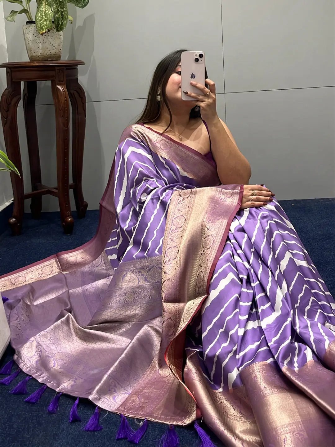 Sitting pose in purple leheriya saree with zari border.